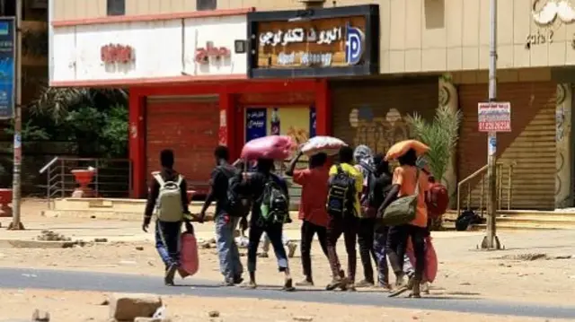 people walk with belongings in khartoum sunday