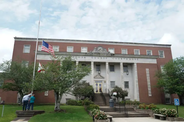 Community members lower a flag outside a Dadeville courthouse to half-mast following the shooting