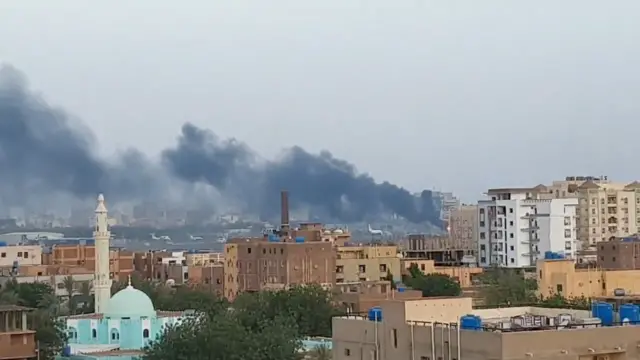 A view over rooftops in Sudan shows smoke rising from the area of Khartoum International Airport