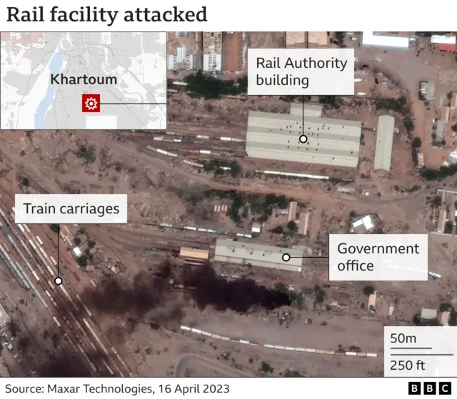 Satellite image of a rail facility in Khartoum, with a smoke plume rising up from near one government office