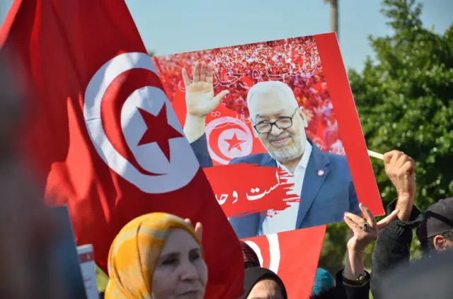 People holding signs and tunisian flags to show support for Ennahdha Movement leader Rached Ghannouchi