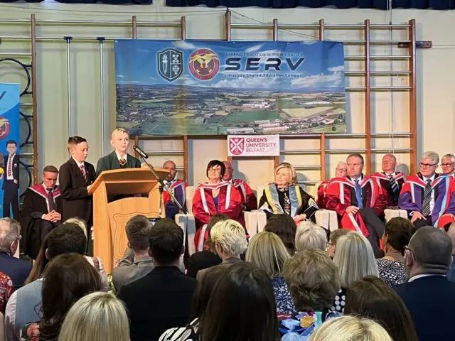 Hilary Clinton watches on in Limavady as school pupils read a poem as part of her welcome.