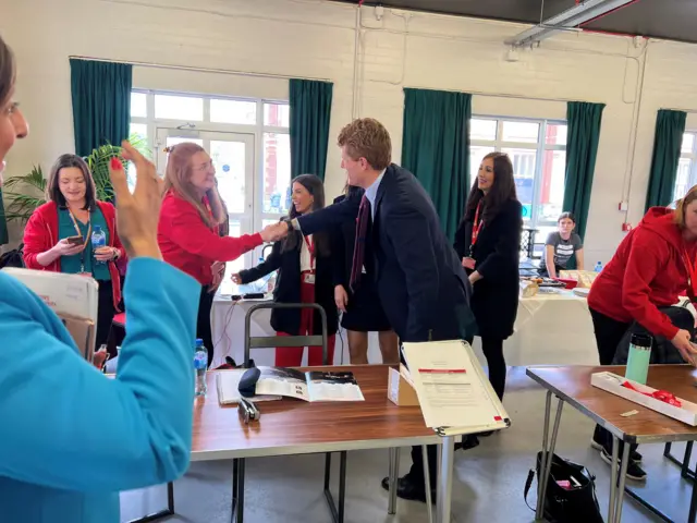 Joe Kennedy shakes hands with QUB staff at the media centre