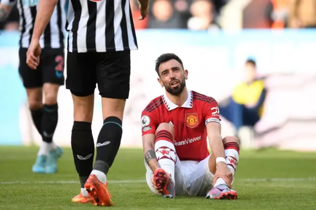 Manchester United's Portuguese midfielder Bruno Fernandes on the floor touching his ankle