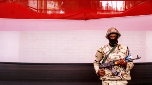 Egyptian soldier standing by flag