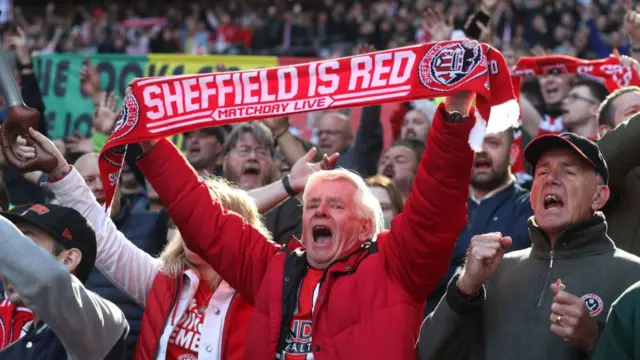 A Sheffield United fan holds his scarf high at Wembley