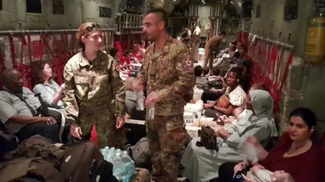 Various people sit in an army aircraft with two officers