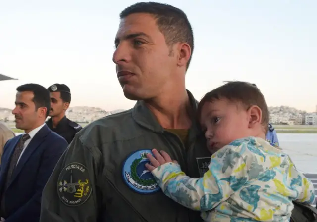 A member of the Royal Jordanian Air Force carries a child as Jordanian citizens and other nationals who were evacuated from Sudan, arrive at Marka Military Airport, in Amman, Jordan, on 25 April 2023