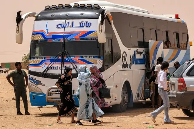 People disembark from a passenger bus in Sudan's Northern State on 25 April 2023