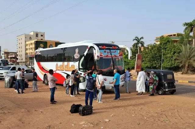 People line up to get on buses in Khartoum on 25 April