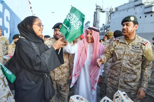 A woman waves a Saudi flag at the port of Jeddah