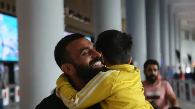 A man smiles as he hugs a child