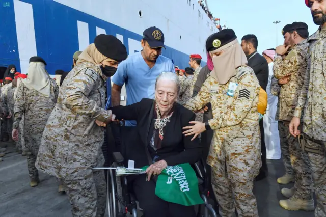 A woman in a wheelchair is helped by security forces at the port of Jeddah