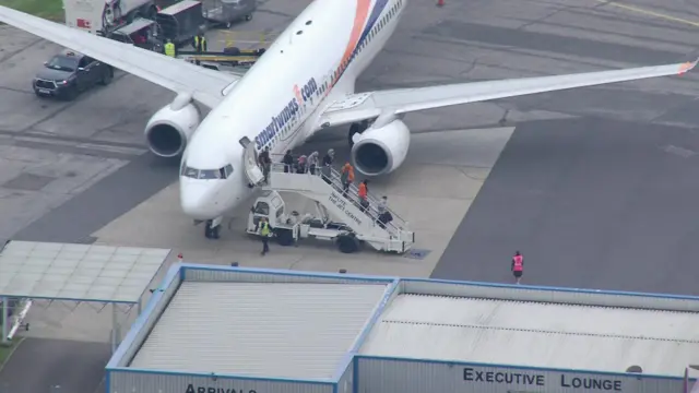 People leave a plane at Stansted airport