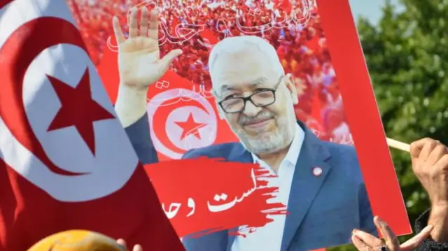 People holding signs and Tunisian flags to show support for Ennahdha Movement leader Rached Ghannouchi