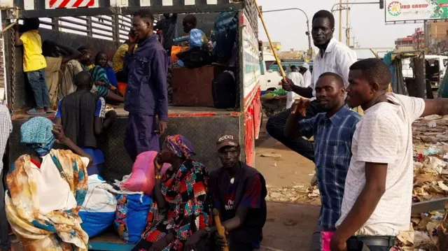 People gather to ride trucks as they flee Khartoum