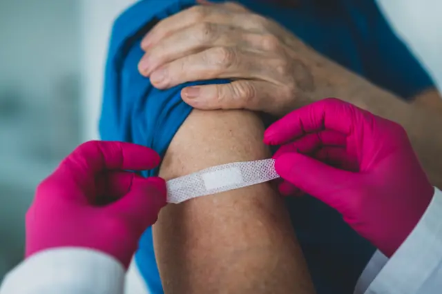 A sticking plaster is applied to a person's arm after they have received an injection