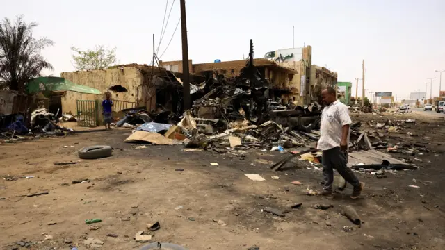 A man walks past damaged buildings