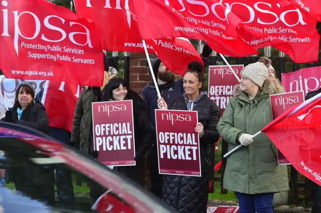 Nipsa members wave flags and hold placards on a picket line