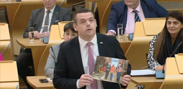 Douglas Ross holding a picture of Humza Yousaf at Ferguson Marine shipyard