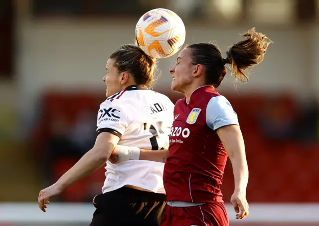 Villa and Utd players engage in an aerial duel.