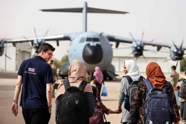 Foreign and Commonwealth Rapid Response team member helps evacuees as British nationals board an RAF aircraft in Sudan, for evacuation to Larnaca International Airport in Cyprus on April 26, 2023 in Khartoum, Sudan.