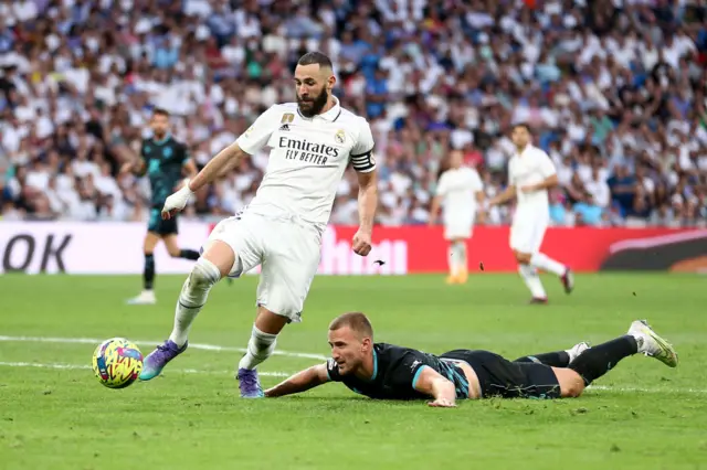 Karim Benzema clips defender Rodrigo Ely while running through on goal.