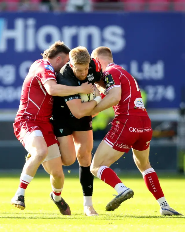 Kyle Steyn is tackled by two Scarlets players