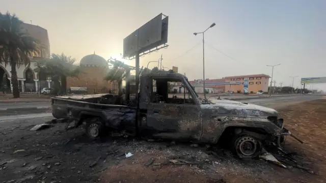 A burned-out vehicle in a deserted street