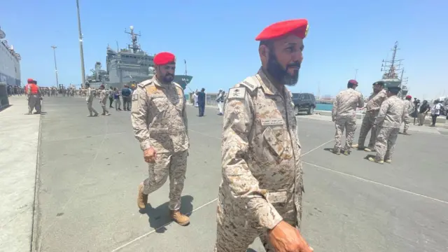 Men in military uniforms walk at a port in Jeddah, Saudi Arabia