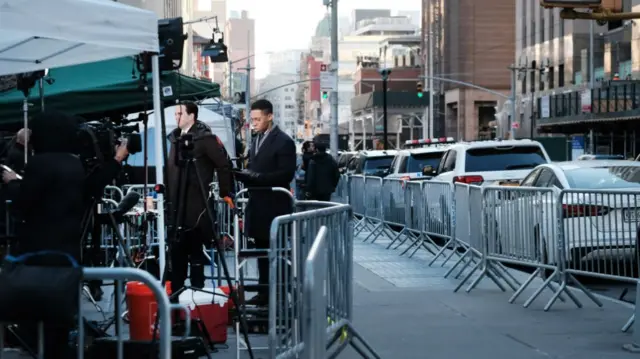 Reporters stand outside the court in Manhattan where Donald Trump will appear on Tuesday