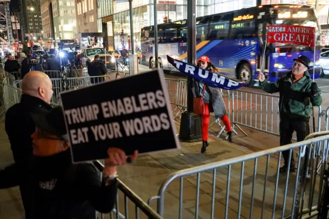 An anti-Trump protester demonstrates while Trump supporters gesture outside Trump Tower