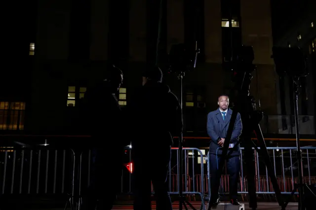 A member of the media reports from outside of New York City courthouse