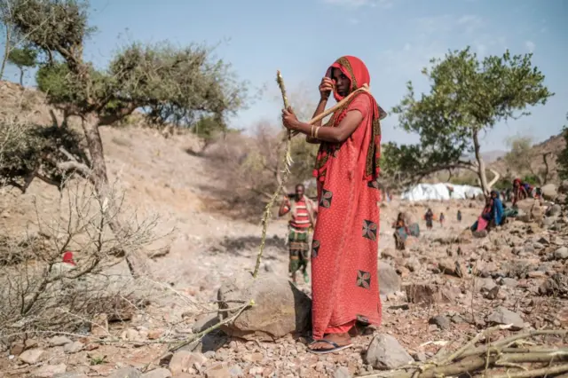 An internally displaced woman looks for somewhere to build a makeshift home.