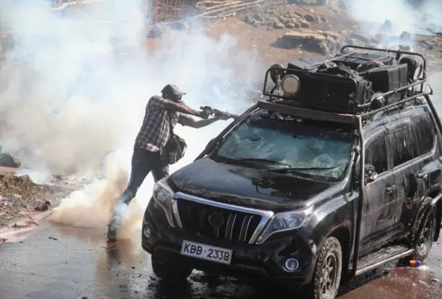 A riot police officer fires teargas canister