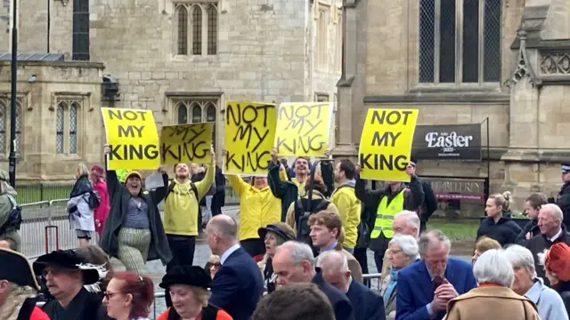 A protest group holding yellow signs