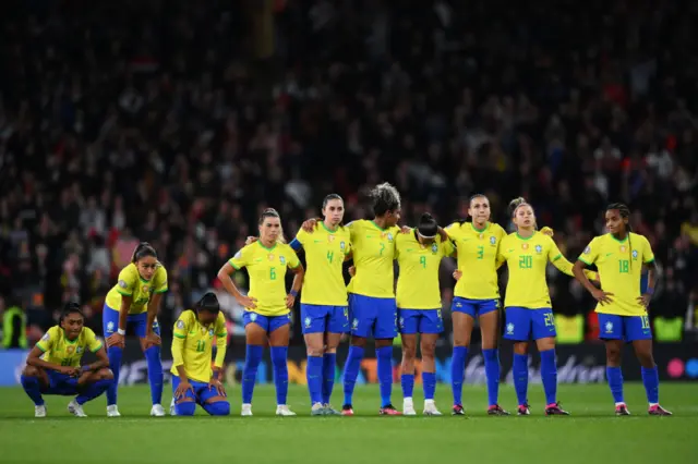 A defeated Brazil watch on as England celebrate their victory.