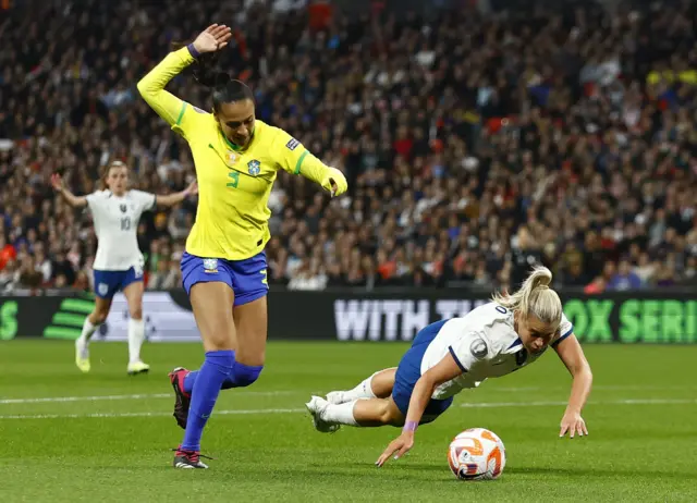 Alessia Russo falls down under a challenge from a Brazil defender.