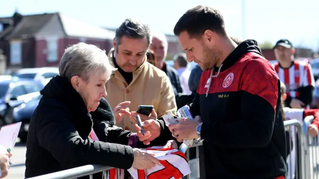 Captain Billy Sharp signs a shirt for a Sheffield United fan