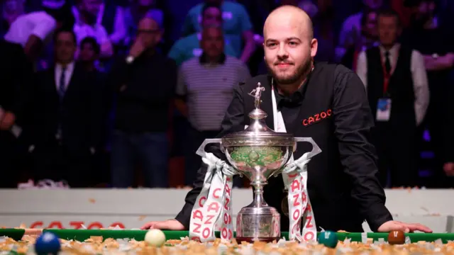 Luca Brecel celebrates with the World Championship trophy