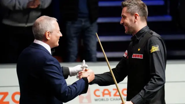 Referee Brendan Moore congratulates Mark Selby on his 147 in the World Championship final