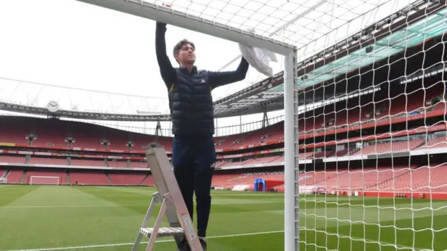 A groundstaff member inside a goal at Arsenal's Emirates Stadium