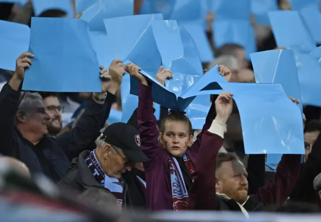 West Ham fans cheer their side onto the pitch.