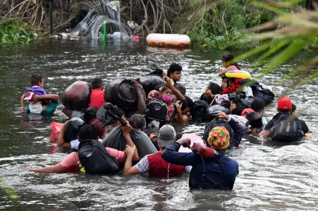 Migrants wade through the Rio Grande to reach the US border