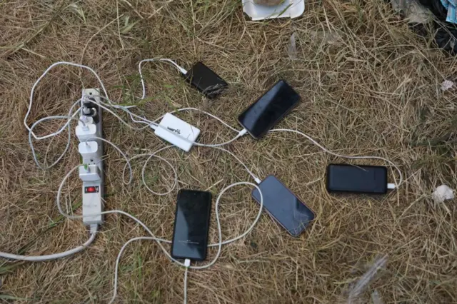 Migrants' cell phones are charged by aid workers in the US as they wait for asylum hearings at the US-Mexico border on May 10, 2023 in San Ysidro, California