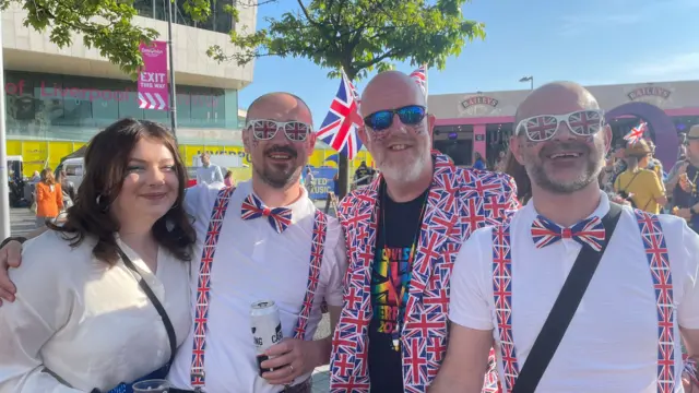 People stand wearing Union Jack jackets and glasses