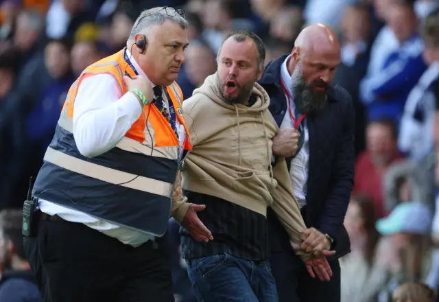 A fan is escorted away by security.