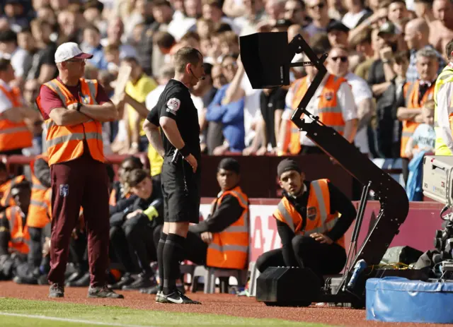 Referee Peter Bankes looks at the VAR monitor before awarding a penalty to Tottenham Hotspur