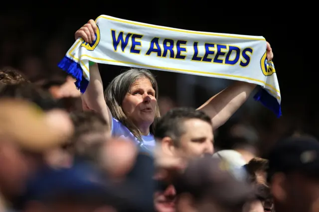 A Leeds fan holds her scarf aloft.