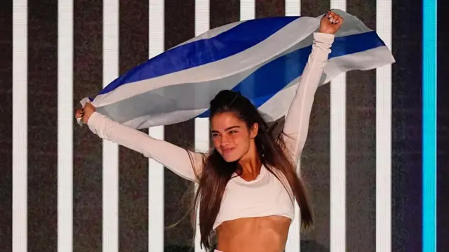 Israel entrant Noa Kirel holds a flag above her head